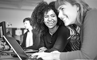 Two women laughing while using a laptop