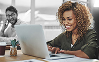 Woman smiling at a laptop screen