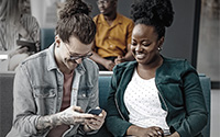 Two people smiling and looing at a mobile device