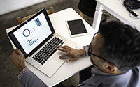 Man looking at a laptop screen that displays charts and graphs.