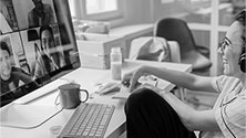 Woman in virtual meeting smiling at a laptop screen.