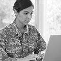Woman in a military uniform using a laptop.