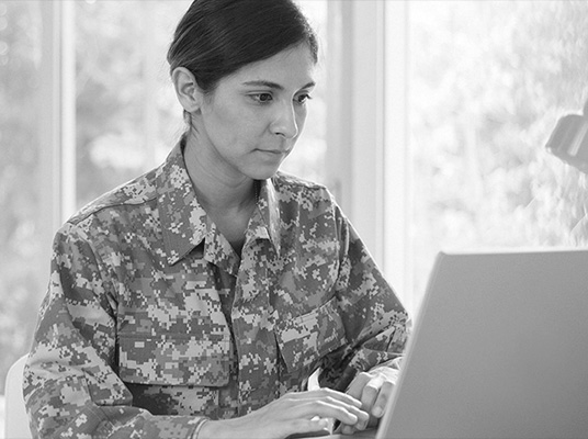 Woman in a military uniform typing on a computer